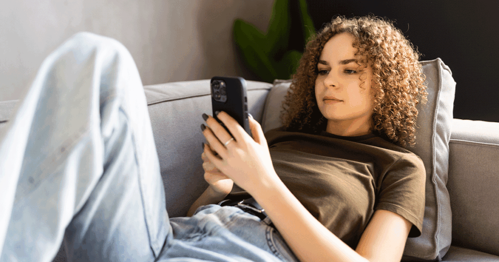 Woman researching abortion information on her phone while considering her pregnancy options.